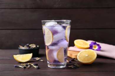 Photo of Organic blue Anchan with lemon in glass on wooden table. Herbal tea