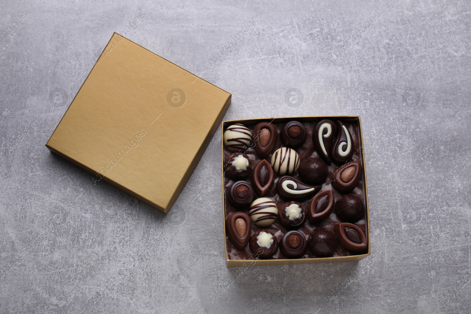 Photo of Open box of delicious chocolate candies on light grey table, top view