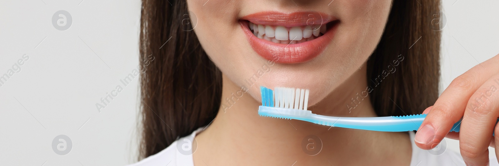 Image of Woman holding plastic toothbrush on white background, closeup. Banner design with space for text