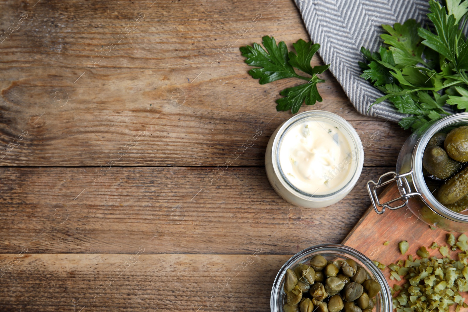 Photo of Tasty tartar sauce and ingredients on wooden table, flat lay. Space for text