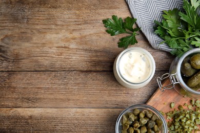 Tasty tartar sauce and ingredients on wooden table, flat lay. Space for text