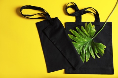 Photo of Flat lay composition with eco tote bags and leaf on color background
