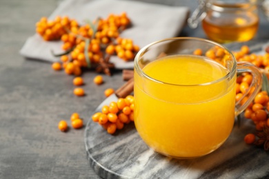 Photo of Delicious sea buckthorn tea and fresh berries on grey table. Space for text