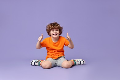 Photo of Happy little boy dancing on violet background. Space for text