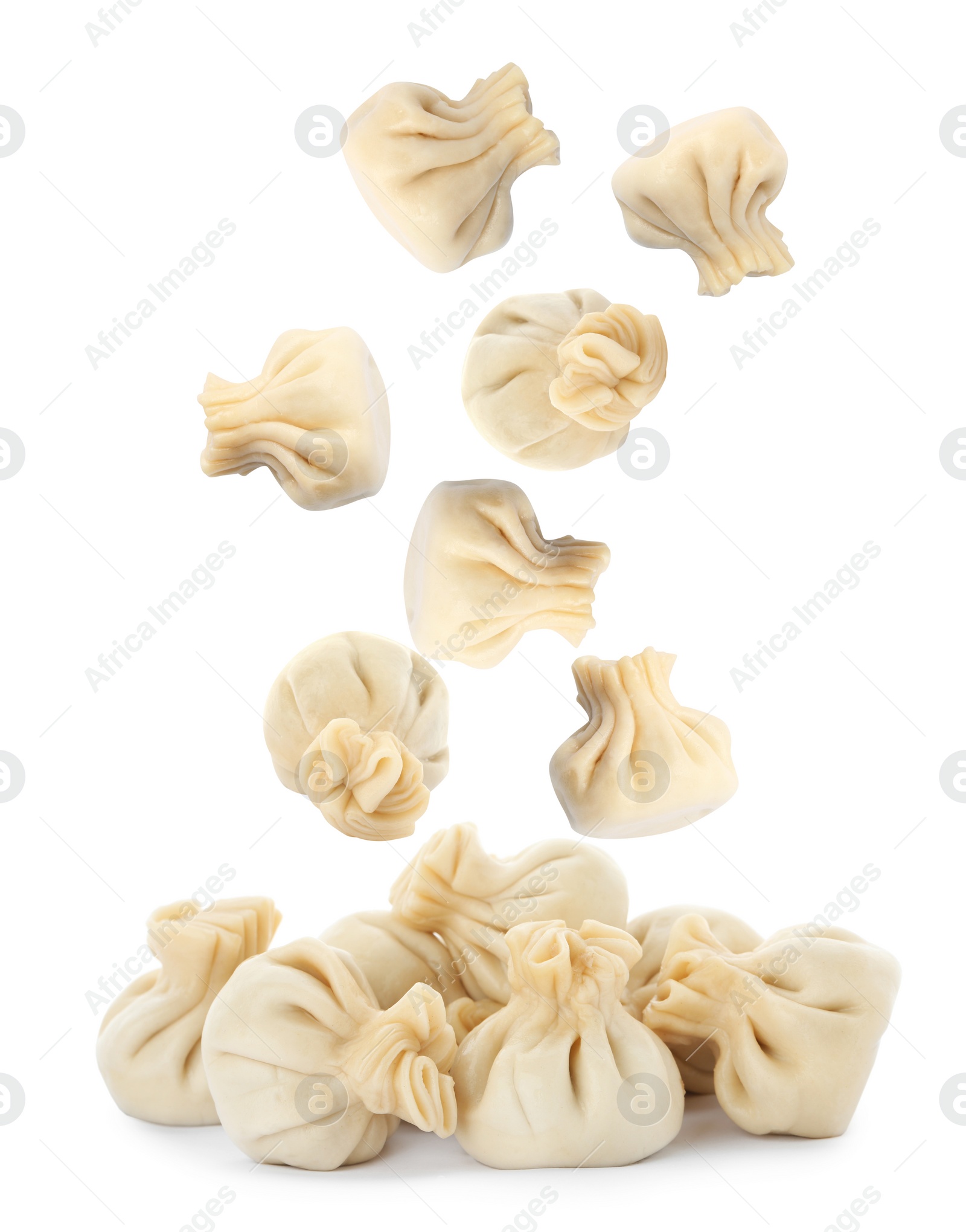 Image of Many tasty dumplings falling on white background