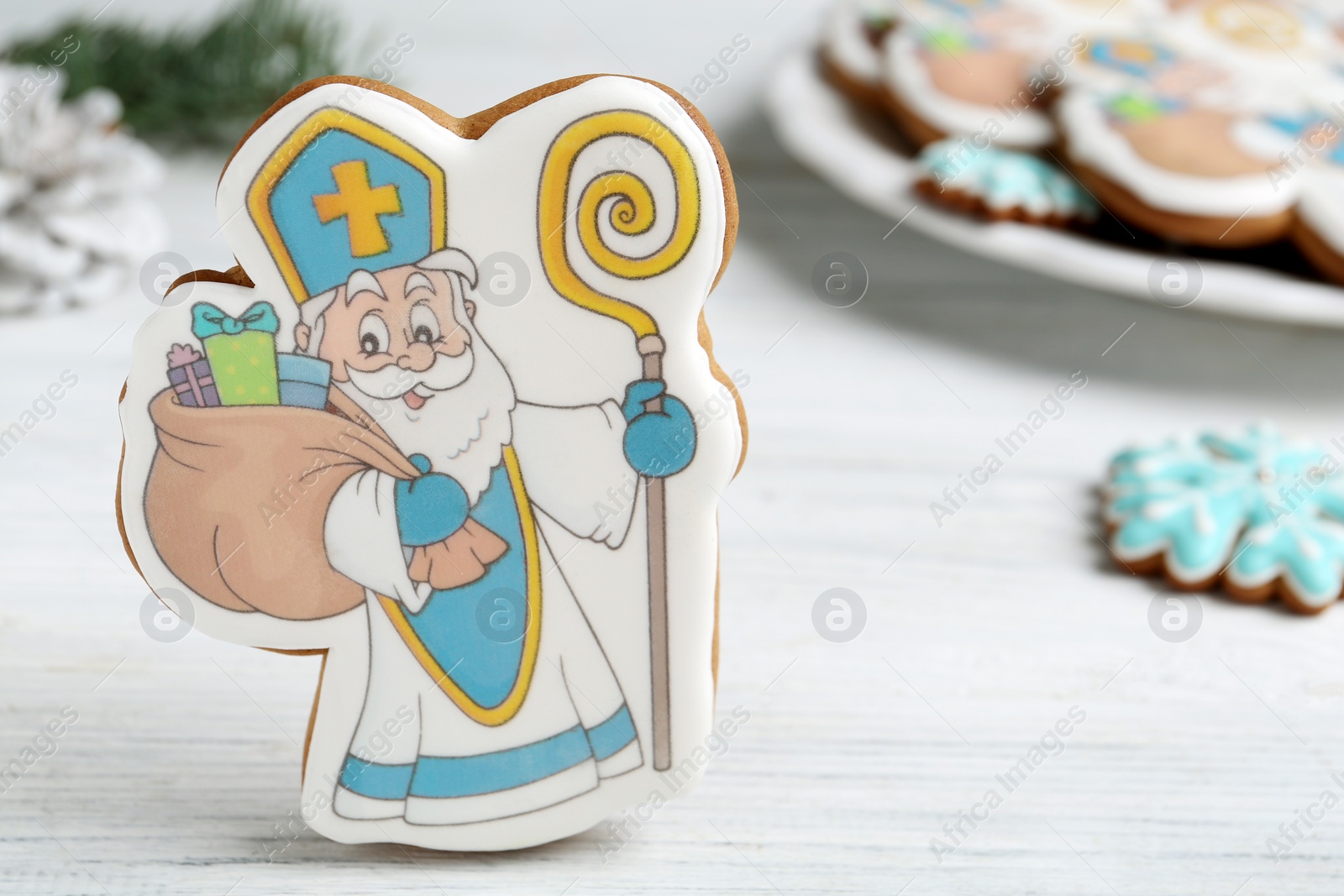 Photo of Tasty gingerbread cookie on white wooden table, closeup view with space for text. St. Nicholas Day celebration