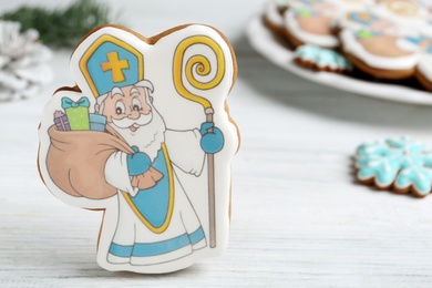 Tasty gingerbread cookie on white wooden table, closeup view with space for text. St. Nicholas Day celebration