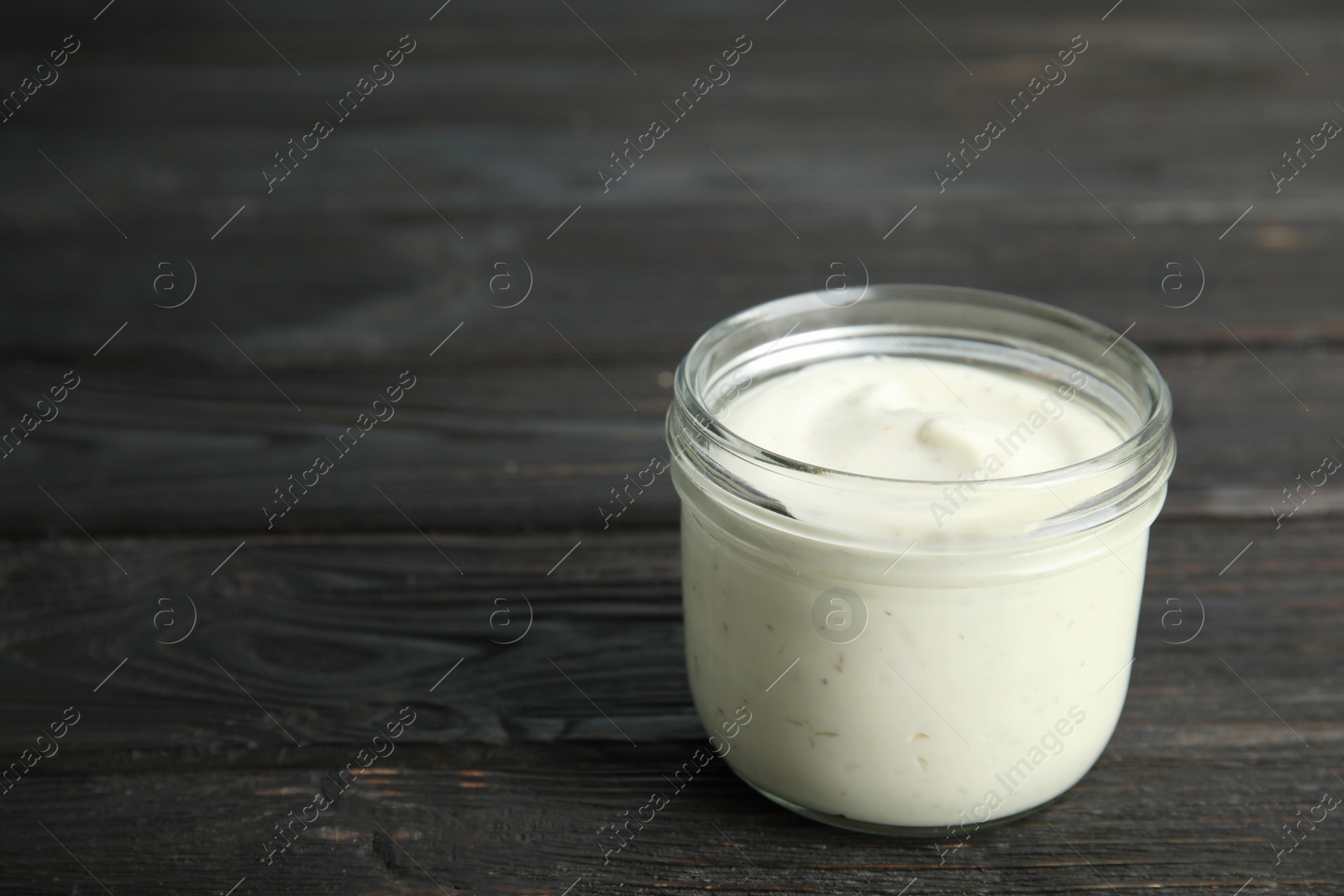 Photo of Jar of garlic sauce on wooden background. Space for text