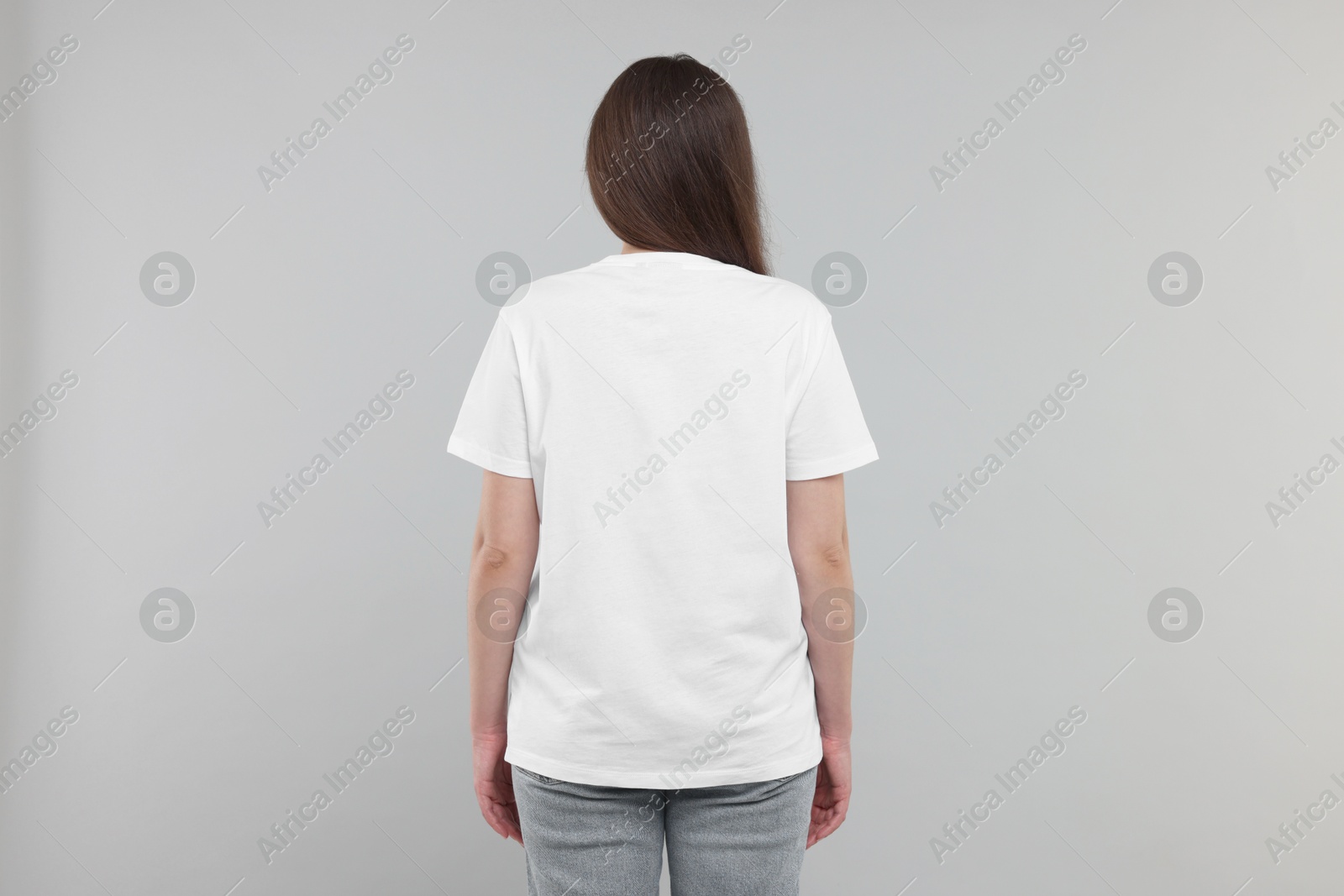 Photo of Woman in white t-shirt on grey background, back view