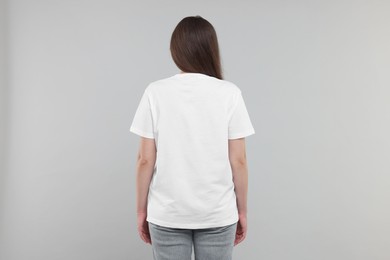 Photo of Woman in white t-shirt on grey background, back view