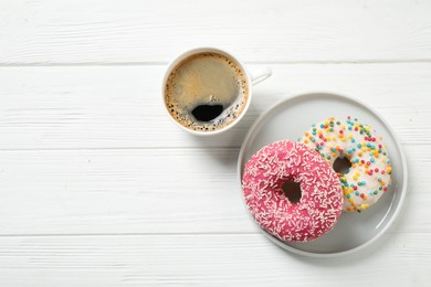 Yummy donuts with sprinkles and coffee on white wooden table, flat lay. Space for text