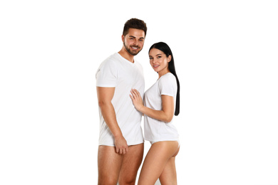Young couple in white t-shirts and underwear on light background