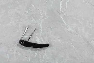 Photo of One corkscrew (sommelier knife) on grey marble table, top view. Space for text