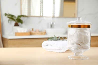 Jar with cotton pads on table in bathroom