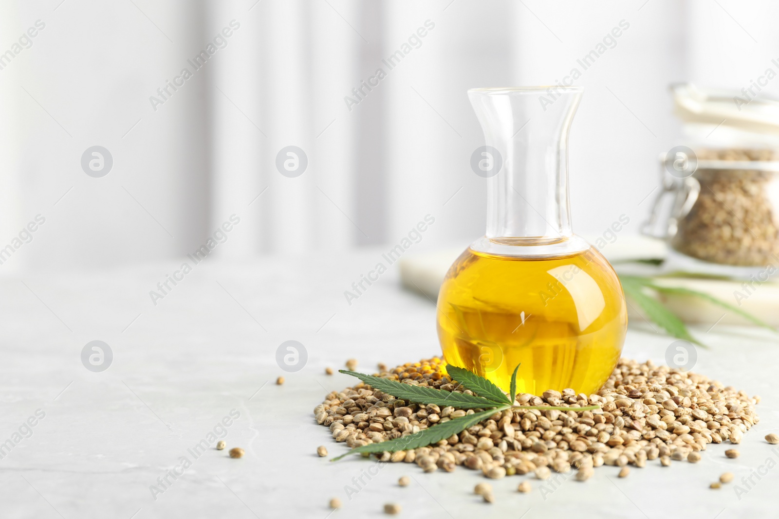 Photo of Bottle with hemp oil, leaf and seeds on white table