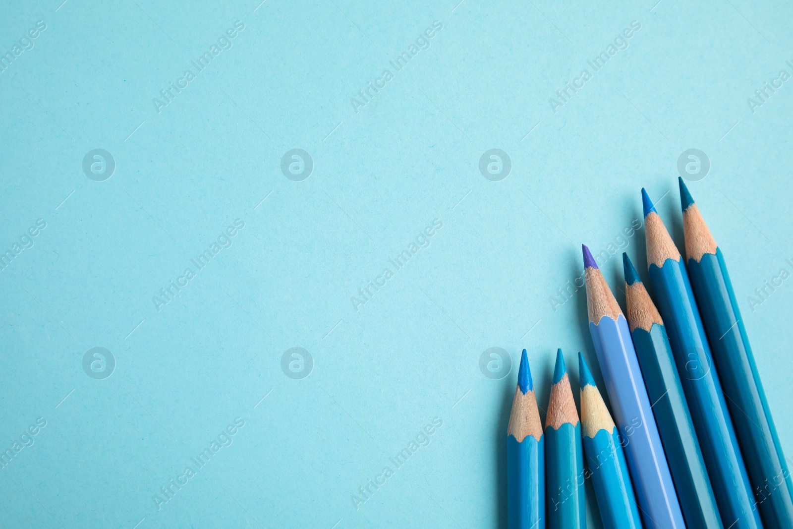 Photo of Flat lay composition with color pencils on light blue background. Space for text