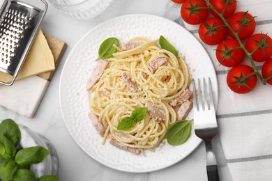 Photo of Plate of tasty pasta Carbonara with basil leaves on white marble table, flat lay