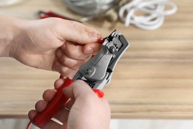 Photo of Professional electrician stripping wiring at wooden table, above view