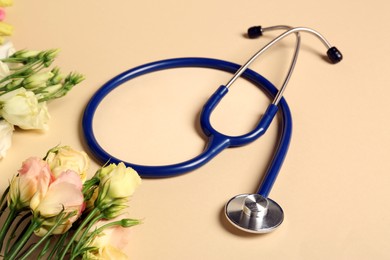 Photo of Stethoscope and eustoma flowers on beige background. Happy Doctor's Day