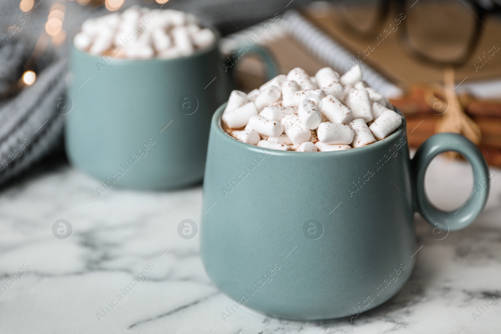 Photo of Delicious hot cocoa drink with marshmallows in cups on white marble table