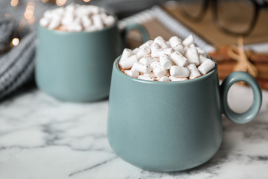 Delicious hot cocoa drink with marshmallows in cups on white marble table
