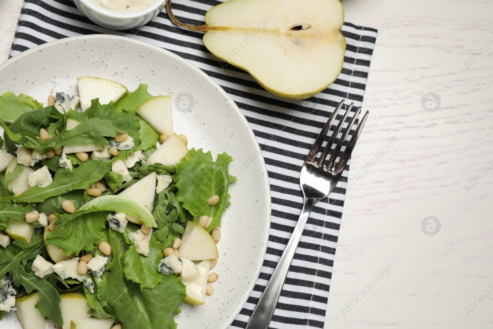 Photo of Tasty salad with pear slices served on white wooden table, flat lay
