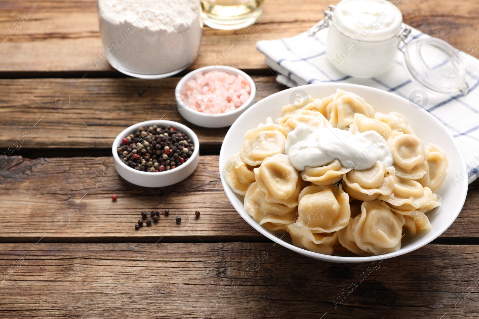Photo of Tasty dumplings in bowl on wooden table, space for text