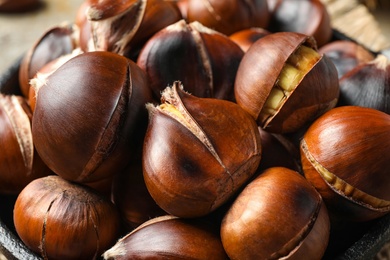 Photo of Tasty roasted edible chestnuts in frying pan, closeup