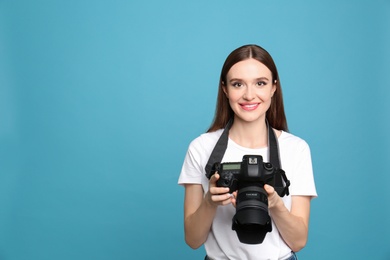 Professional photographer with modern camera on light blue background