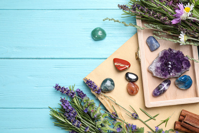 Photo of Gemstones and healing herbs on light blue wooden table, flat lay. Space for text