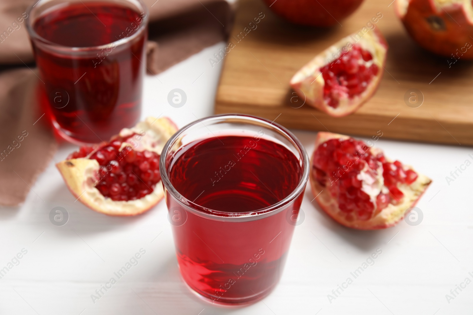 Photo of Freshly made pomegranate juice on white wooden table