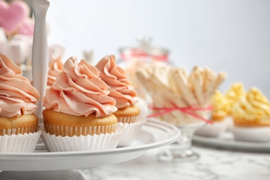 Stand with tasty cupcakes on table, space for text. Candy bar