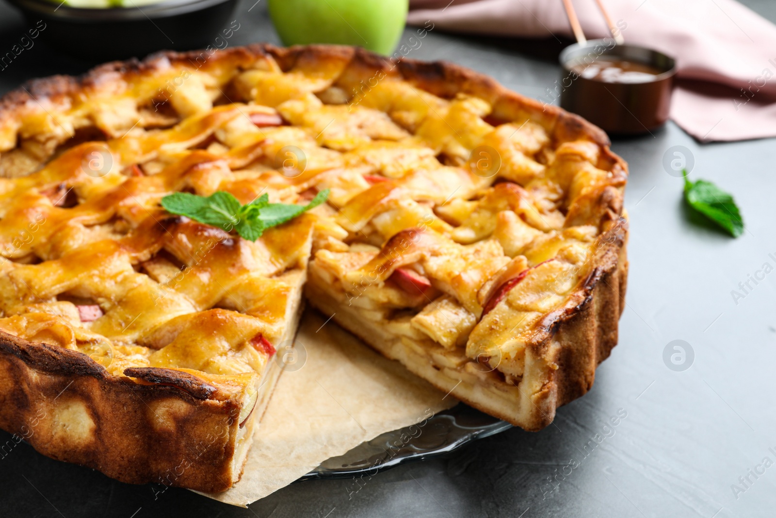 Photo of Traditional apple pie with mint on light grey table, closeup