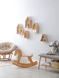 Photo of House shaped shelves and rocking horse in children's room. Interior design