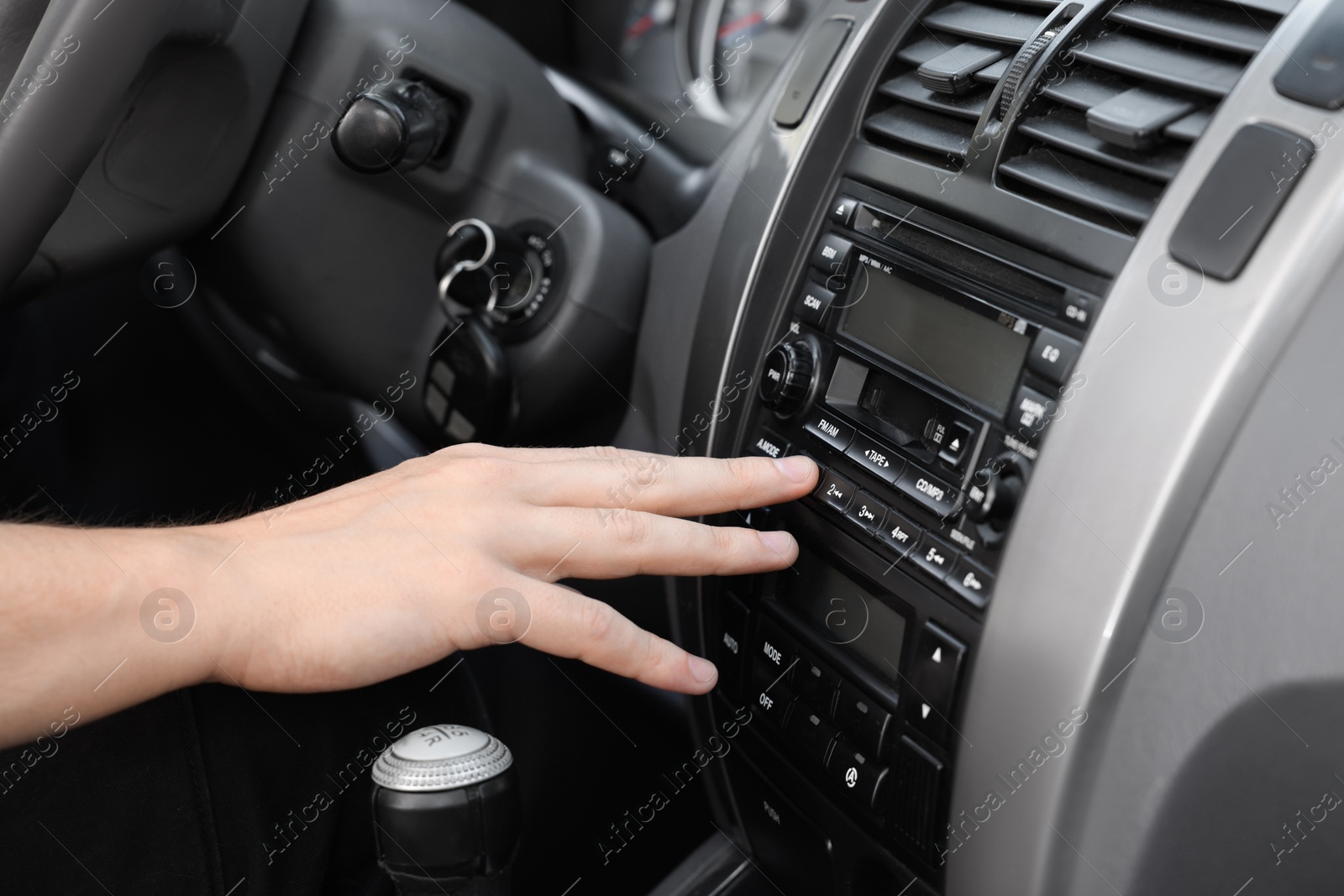 Photo of Choosing favorite radio. Woman pressing button on vehicle audio in car, closeup