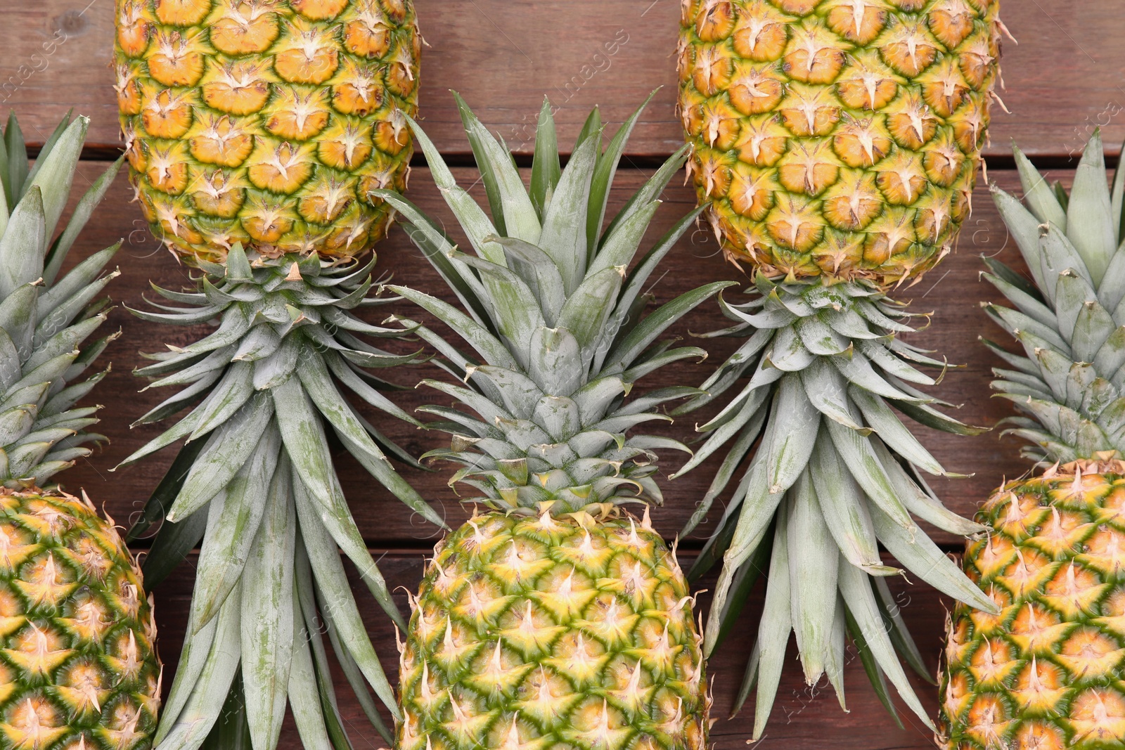 Photo of Delicious ripe pineapples on wooden table, flat lay