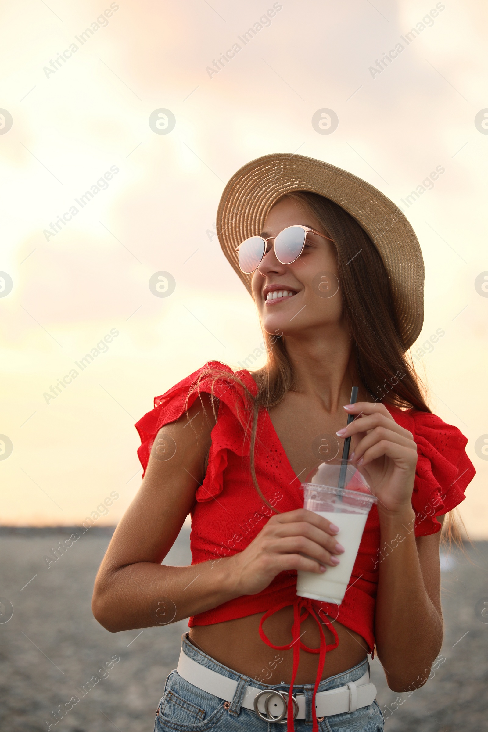 Photo of Beautiful young woman with tasty milk shake on beach