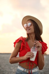 Photo of Beautiful young woman with tasty milk shake on beach