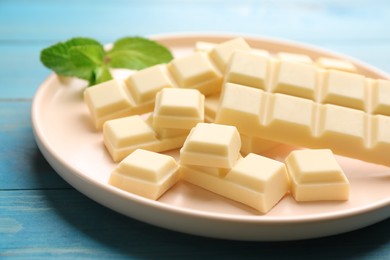 Photo of Delicious white chocolate and mint on light blue wooden table, closeup