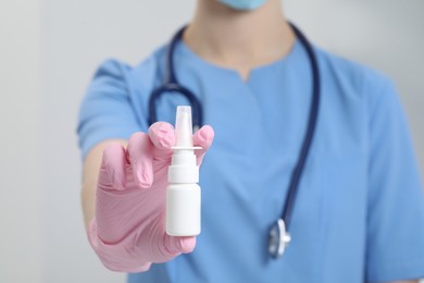 Doctor holding nasal spray on white background, closeup