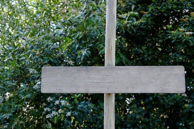 Photo of Small blank wooden signpost near bushes outdoors