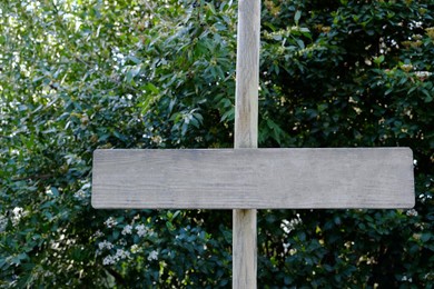 Small blank wooden signpost near bushes outdoors