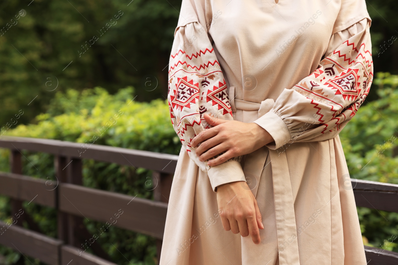 Photo of Beautiful woman wearing embroidered dress in countryside, closeup with space for text. Ukrainian national clothes