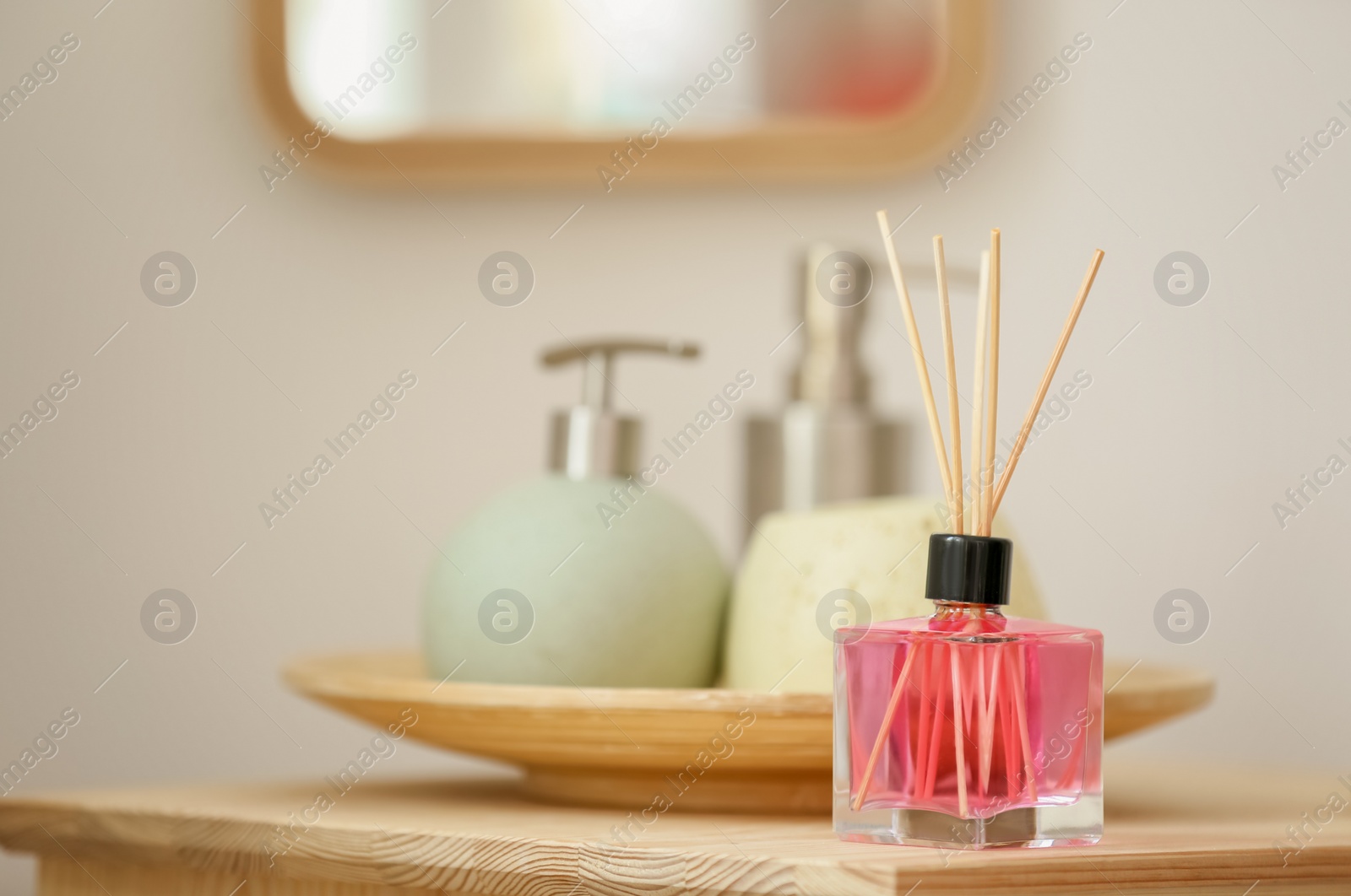 Photo of Aromatic reed air freshener and toiletries on table indoors