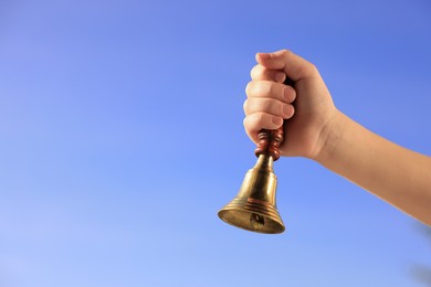 Photo of Pupil with school bell against beautiful sky, closeup. Space for text