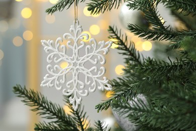 Closeup of beautiful bauble in shape of snowflake hanging on Christmas tree