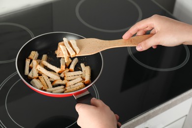 Photo of Woman cooking hard chucks on cooktop, closeup