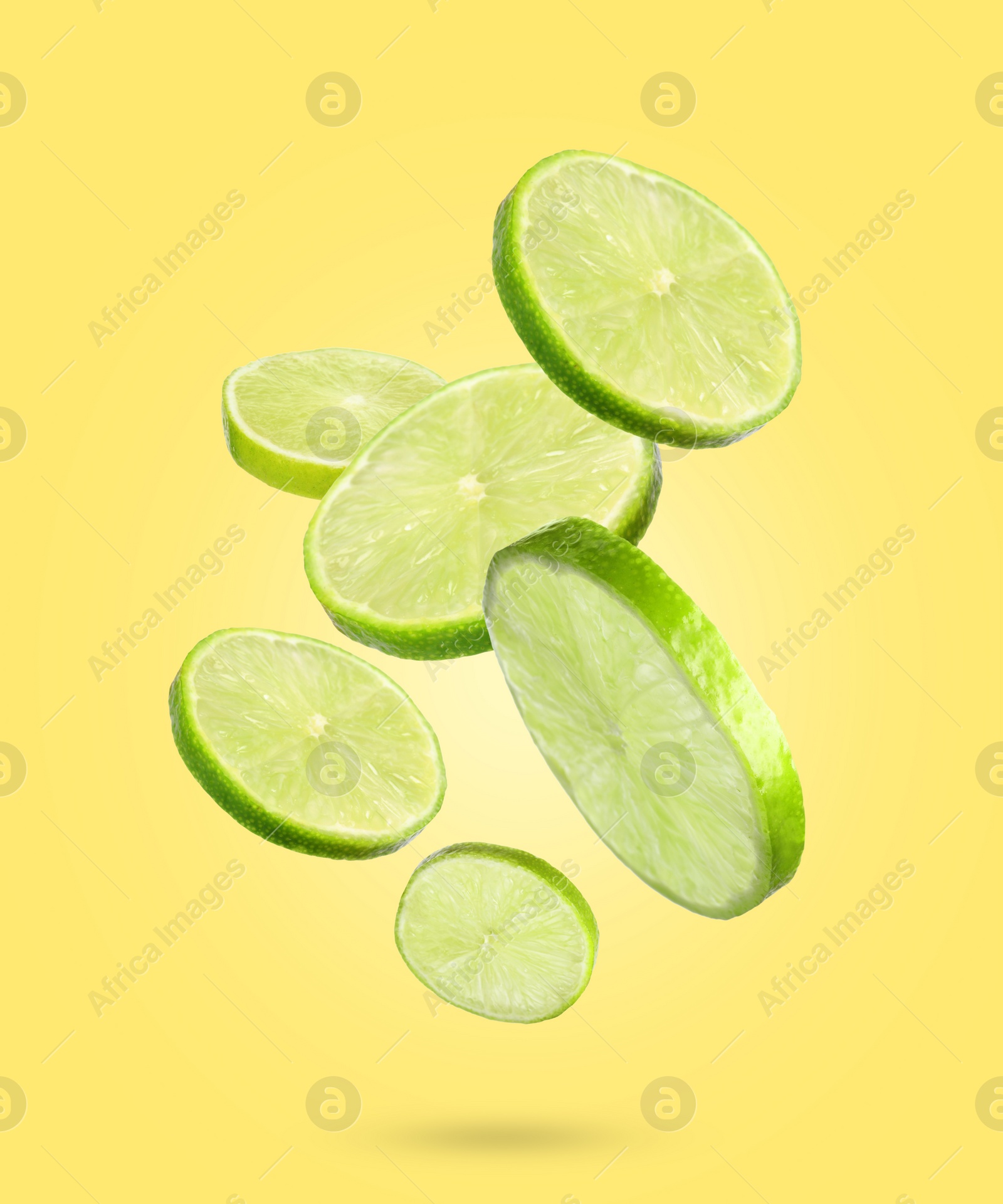 Image of Fresh lime slices falling on yellow background