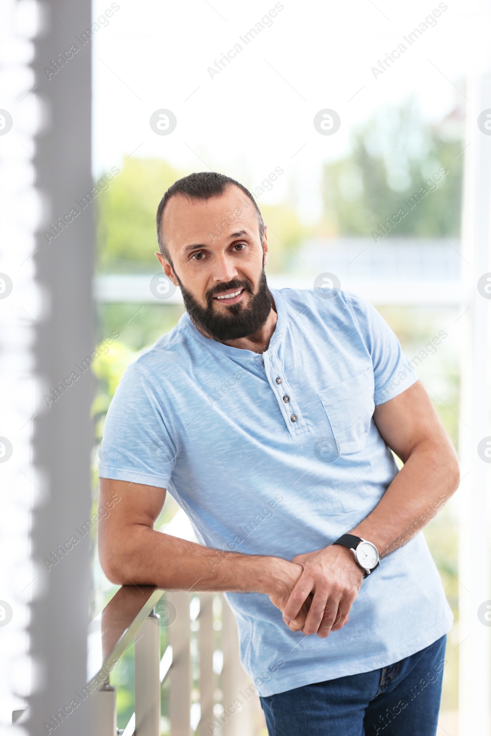 Photo of Portrait of handsome mature man leaning on handrail indoors