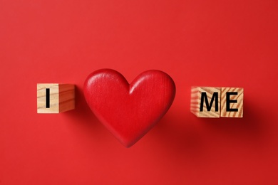 Photo of Phrase I Love Me made with wooden cubes and heart on red background, flat lay